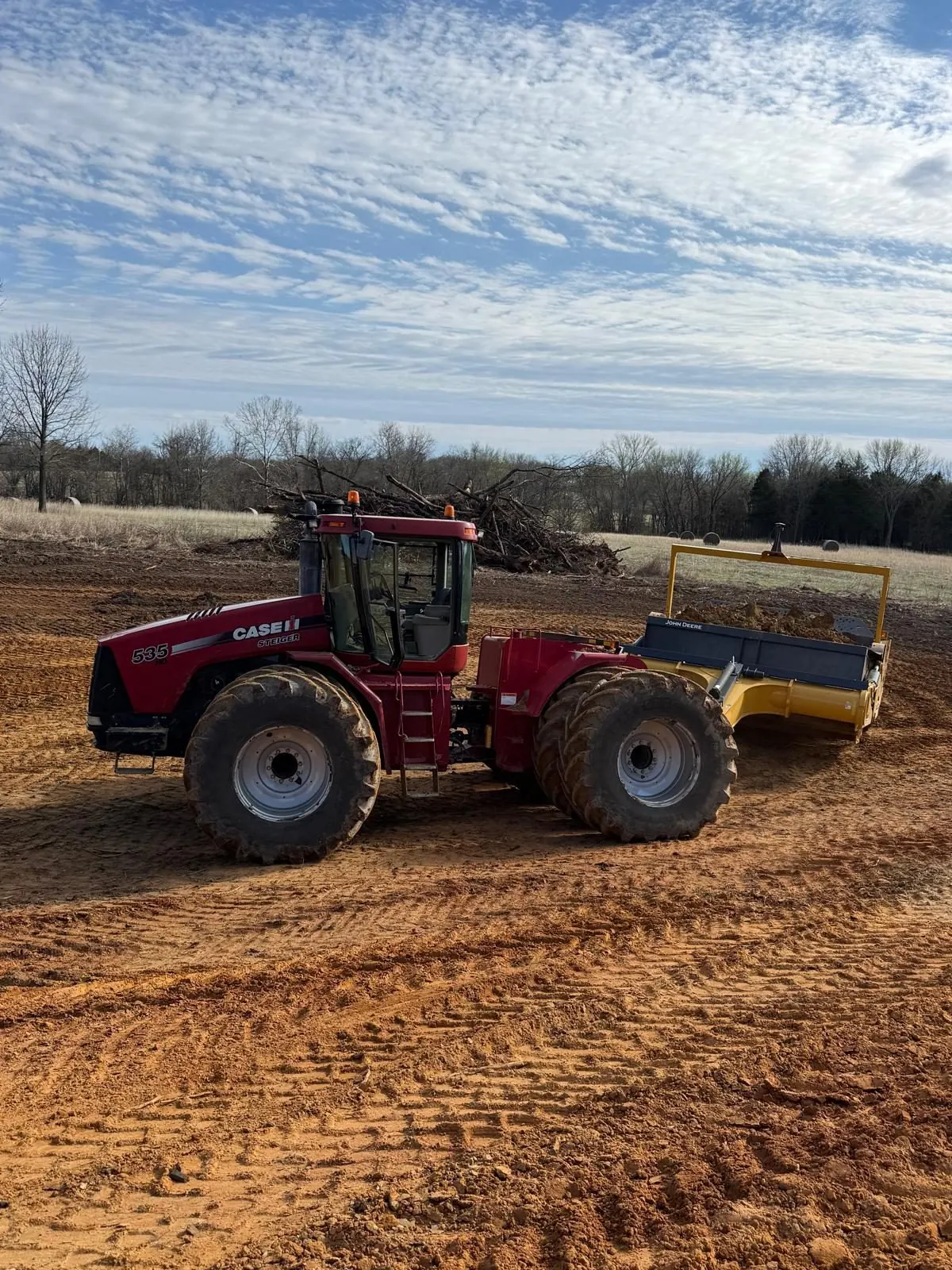 Case tractor pulling an earth scraper