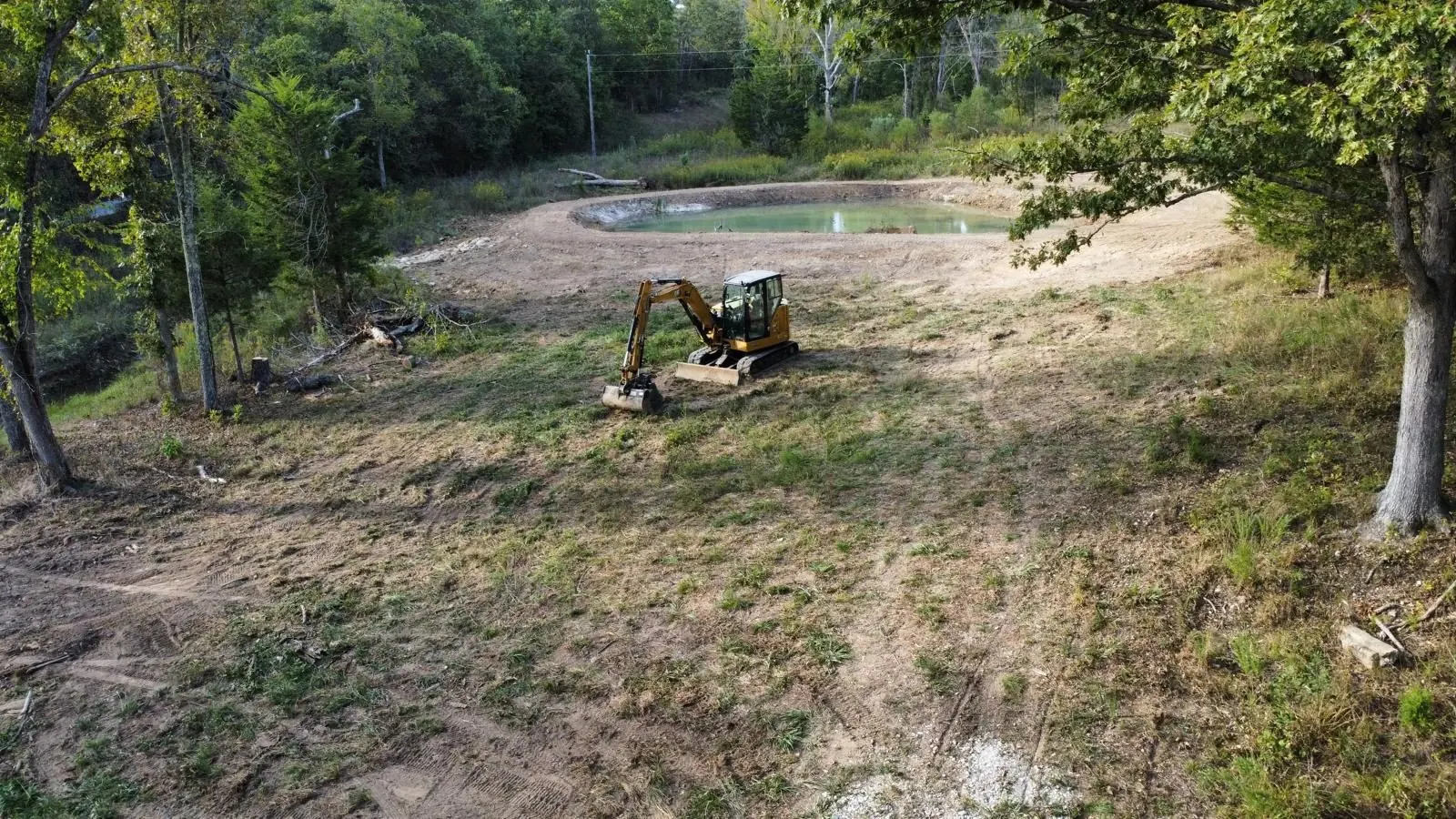 Mini excavator working beside a pond