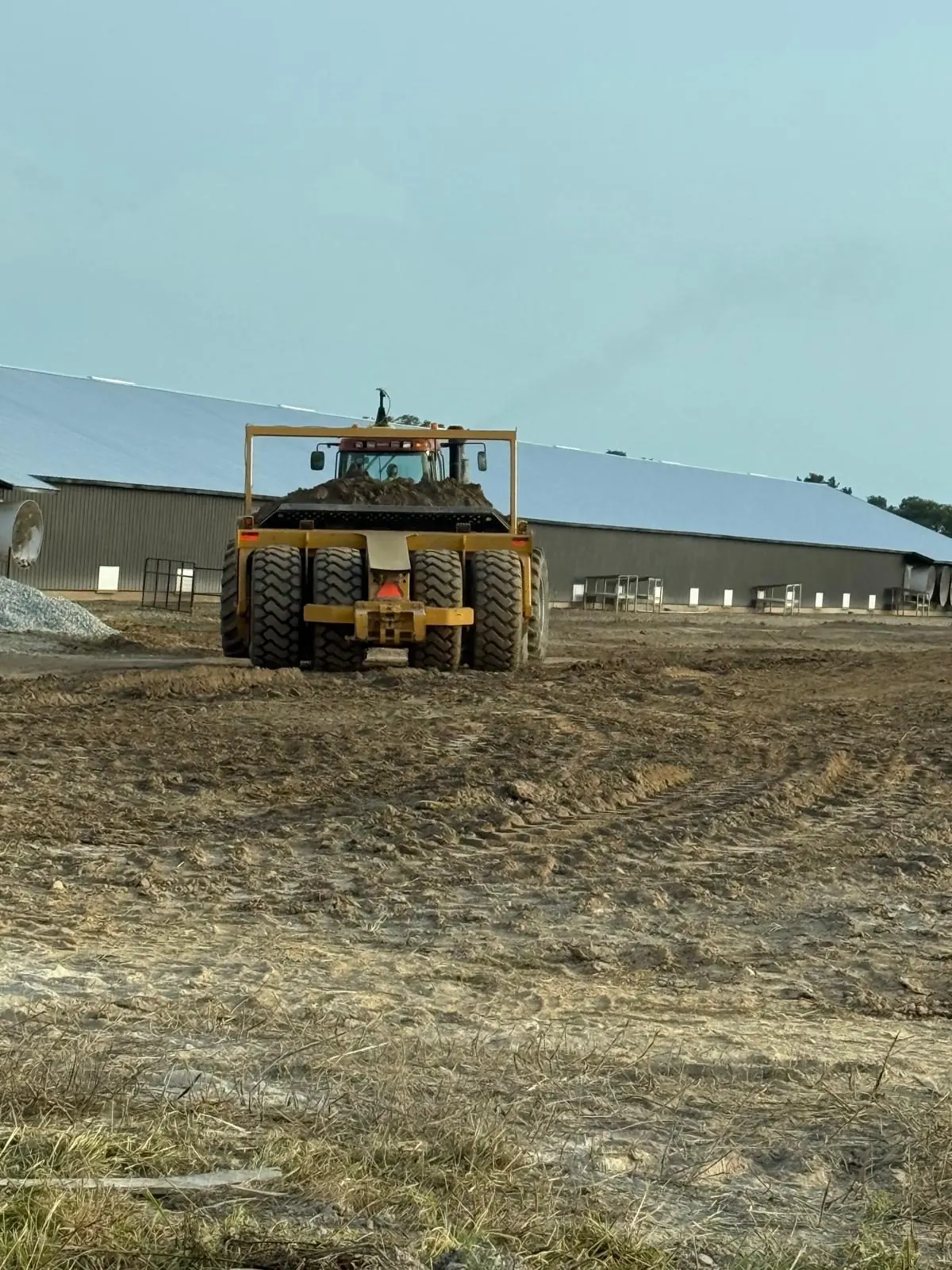 Earth scraper working beside a barn